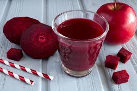 "A refreshing glass of apple beetroot juice with a slice of apple and beetroot on the side"