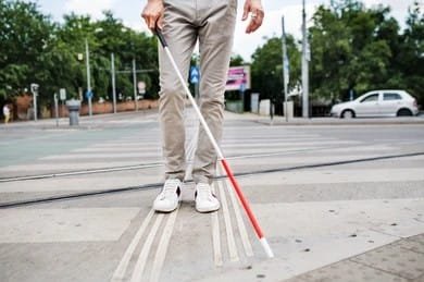 Visually impaired person navigating road with white cane